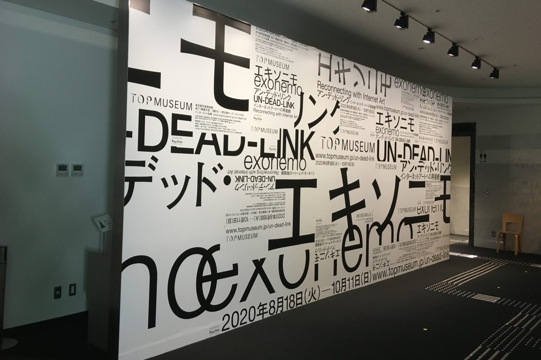 展覧会入口、巨大ポスターボード、エキソニモという文字がグラフィカルに配置